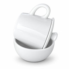A glossy white ceramic mug with a matching lid resting inside a white ceramic bowl, photographed on a clean white background.